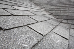 Asphalt shingle roof with chalk-encircled dings caused by hail